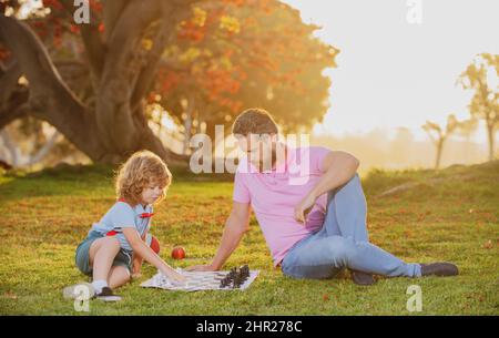 École d'échecs pour enfants. Père et fils jouant aux échecs et passant du temps ensemble à l'extérieur. Banque D'Images