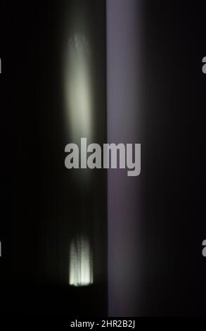 La première lumière du jour se reflète sur un mur de chambre et dans un miroir créant des formes abstraites lumineuses curieuses. Banque D'Images
