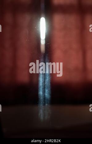 La première lumière du jour se reflète sur un mur de chambre et dans un miroir créant des formes abstraites lumineuses curieuses. Banque D'Images
