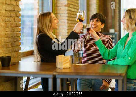 Des amies ravies se clinquantes à côté de la fenêtre du bar Banque D'Images