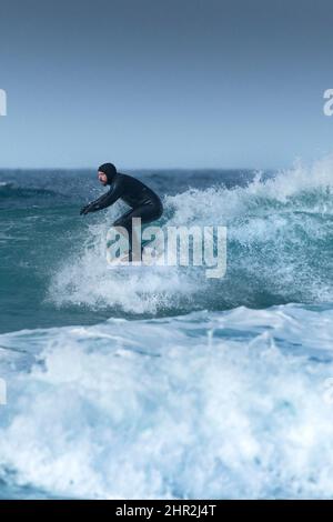 Un surfeur qui profite d'une spectaculaire action de surf en hiver à Fistral à Newquay, en Cornouailles, au Royaume-Uni. Banque D'Images