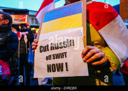 Un manifestant bélarussien est muni d'un écriteau avec un drapeau ukrainien et l'inscription « Cut Russia Off SWIFT Now! » pendant la manifestation. En réponse à l'invasion russe de l'Ukraine, des membres de la communauté ukrainienne et des Polonais et des Biélorusses ont protesté près des missions diplomatiques de la Fédération de Russie pour exprimer leur opposition à l'agression militaire russe. À Cracovie, où l'immigration ukrainienne est particulièrement importante, plusieurs milliers de personnes ont défilé dans le centre-ville et se sont rassemblées devant le consulat russe. Banque D'Images