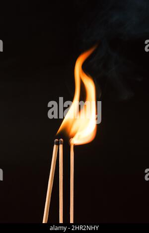 Gros plan de trois allumettes en feu isolées sur fond noir Banque D'Images