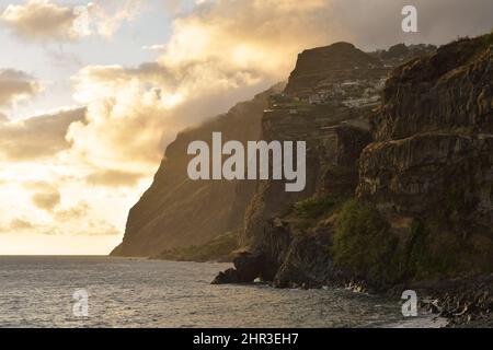 Cabo Girao, hautes falaises volcaniques vues de la plage de Praia de Vigário au crépuscule, situé sur la côte sud de Madère Portugal. Banque D'Images