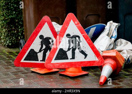 Les hommes au travail des panneaux, des cônes de signalisation et des panneaux dans le jardin domestique Banque D'Images