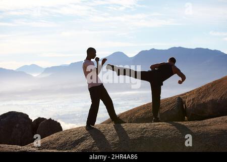 Formation en montagne. Deux kickboxers pour hommes s'entraîner sur un sommet de montagne. Banque D'Images