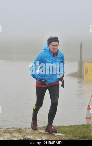 une femme plus âgée qui court à travers le club de course de cross-country risque d'eau Banque D'Images