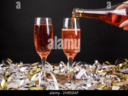 Personne versant du champagne rouge sur un verre avec des banderoles Banque D'Images