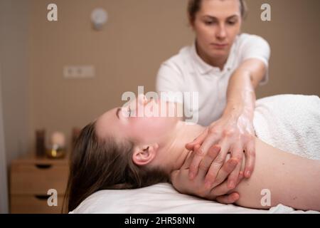 Gros plan physiothérapeute expérimenté faisant un massage de muscle de poitrine à la jeune femme caucasienne. Plan détaillé d'une masseuse non reconnaissable appliquant pressur Banque D'Images