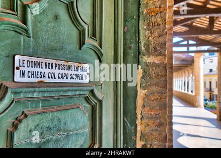 Un panneau indiquant "les femmes ne peuvent pas entrer avec leur tête découverte" à l'entrée de la Collégiata di San Michele Arcangelo, Città Sant'Angelo, Banque D'Images