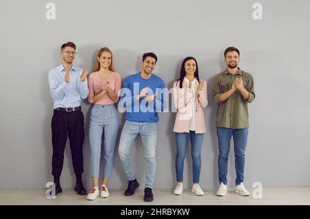 Des jeunes amicaux et heureux qui réussissent se tiennent dans la ligne et applaudissent leur chef. Banque D'Images