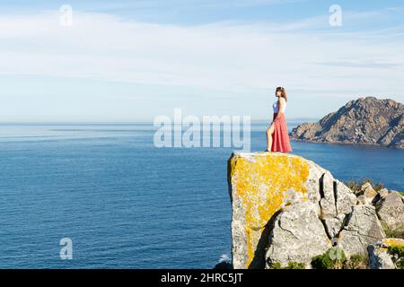 Femme debout au bord d'une falaise rocheuse dans les îles Cies, Galice, Espagne Banque D'Images