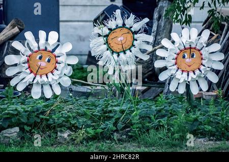 Fleurs avec sourires faites de bouteilles en plastique dans le jardin Banque D'Images