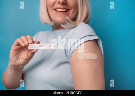 Gros plan de la femme ayant un test d'antigène avec un résultat négatif pour la pandémie de COVID-19, montrant le bras avec le plâtre sur fond bleu clair Banque D'Images