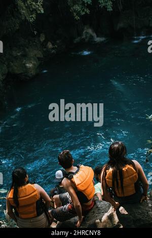 Plan vertical des trois jeunes portant des gilets vivants et regardant l'eau Banque D'Images