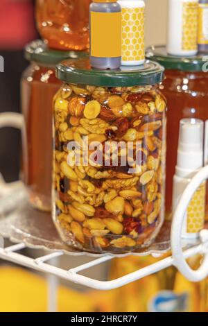 Mélange de noix dans un pot en verre et miel d'abeille aliments sucrés Banque D'Images