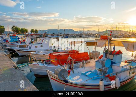 Des bateaux de pêche colorés rouge, blanc et bleu bordent le port de l'île grecque d'Aegina, Grèce, au coucher du soleil. Banque D'Images