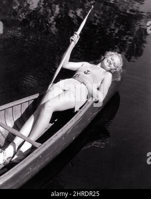 1930S FEMME BLONDE SOURIANTE PORTANT UN MAILLOT DE BAIN TENANT UN OAR ALLONGÉ DANS UN CANOT EN BOIS REGARDANT VERS LE HAUT APPAREIL PHOTO - C1568 HAR001 FEMMES HARS RURAL SANTHINESS COPY SPACE FEMMES PLEINE LONGUEUR FITNESS PERSONNES BAINS DE SOLEIL CONFIANCE TRANSPORT B&W ÉTÉ CONTACT VISUEL CANOË BONHEUR GAI CANOTS GRAND ANGLE LOISIR RÉCRÉATION SOURIRES SOLEIL JOYEUSE OAR ÉLÉGANT MAILLOT DE BAIN SAISON DE RELAXATION JEUNE FEMME ADULTE NOIR ET BLANC RACE BLANCHE HAR001 ANCIENNE Banque D'Images