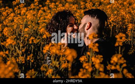 Un jeune couple heureux sur le point de s'embrasser au milieu d'un champ de fleurs d'orange au printemps Banque D'Images