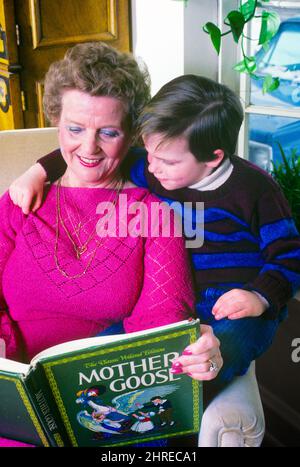 1980S PETIT-FILS ASSIS SUR LE BRAS DE LA CHAISE, BRAS AUTOUR DE LA FEMME, SA GRAND-MÈRE, COMME ELLE LE LIT DE SA MÈRE GOOSE LIVRE - KJ11212 TRA001 HARS GRAND-MÈRE TEMPS VIEUX NOSTALGIE VIEILLE MODE 1 STYLE JUVÉNILE COMMUNICATION TRAVAIL D'ÉQUIPE GRANDS-PARENTS FORTS HEUREUX FAMILLES JOIE STYLE DE VIE SATISFACTION AÎNÉS FEMMES GRAND-PARENT MAISON VIE COPIE ESPACE AMITIÉ DEMI-LONGUEUR FEMMES PERSONNES S'OCCUPANT HOMMES SENIOR ADULTE SENIOR SENIOR FEMME GOOSE BONHEUR VIEILLESSE OLDSTERS GAIETÉ OLDSTER SA ELLE COMME DE SUR LES GRANDS-MÈRES SOURIT CHANDAILS ANCIENS CONNEXION PETIT-FILS JOYEUSE MÈRE GOOSE ATTACHEMENT PERSONNEL AFFECTION ÉMOTION Banque D'Images