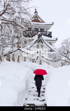 Randonnée touristique sur la neige avec parapluie rouge avec le château de Yokote, Yokote, préfecture d'Akita, Japon Banque D'Images