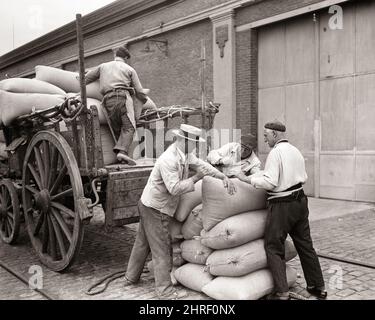 1930S 1940S QUATRE HOMMES DÉCHARGEANT DES SACS DE GRAIN DE CHARIOT EN BOIS MONTEVIDEO URUGUAY - S143 PAL001 HARS B&W AMÉRIQUE DU SUD COMPÉTENCES D'OCCUPATION SUD-AMÉRICAINE HAUTE ANGLE DÉCHARGEANT LE TRAVAIL DES PROFESSIONS SACS PAILLE HAT INFRASTRUCTURE EMPLOYÉ BERET COOPÉRATION NOIR ET BLANC HISPANIQUE ETHNICITÉ LABÉRANT À L'ANCIENNE Banque D'Images