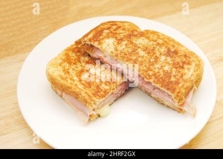 Sandwich au jambon et au fromage grillés servi sur une assiette blanche Banque D'Images