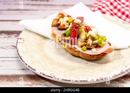 Vue imprenable sur une bruquette de pain rustique avec de la charcuterie, des champignons et de la vinaigrette, arrosée d'EVOO ou d'huile d'olive. Tapa typiquement espagnol. Banque D'Images