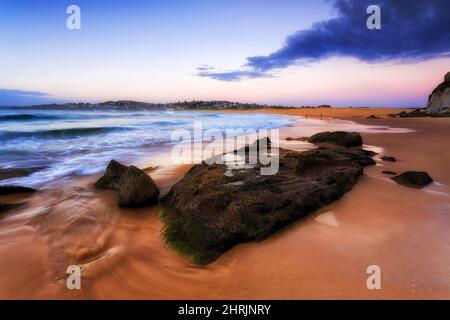 Gros rocher érodé sur la plage de Curl Curl au lever du soleil - plages du nord de Sydney. Banque D'Images