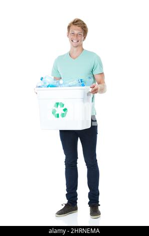 Chaque petit bit aide. Un jeune homme heureux à tête rouge tenant un bac de recyclage rempli de bouteilles en plastique vides. Banque D'Images