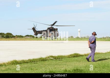 Entrer pour un terrain. Un hélicoptère atterrit sur un launchpad tandis qu'un officier se tient sur le côté. Banque D'Images