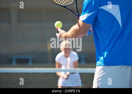 Vous êtes prêt pour cela. Image rognée d'un homme qui rebondit une balle de tennis dans sa main avant un service. Banque D'Images