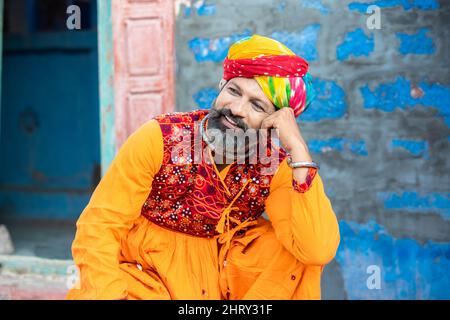 Portrait d'un homme indien du nord traditionnel heureux portant une tenue colorée assis. Un homme rajasthan souriant avec des tenues turban et ethniques. Culture et saf Banque D'Images