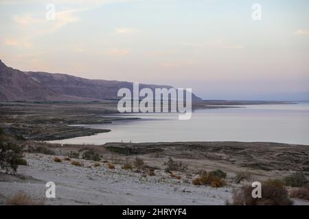 Un homme est assis sur le rivage de la mer Morte Un homme assis yoga dans une île tropicale avec le ciel de blus et le blues gradient de l'océan à la rive. Banque D'Images