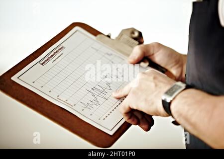 Suivi du marché à long terme. Personne pointant vers un graphique dans un presse-papiers. Banque D'Images