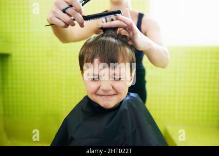 Sa première coupe de cheveux. Coupe courte d'un jeune garçon avec sa première coupe de cheveux. Banque D'Images