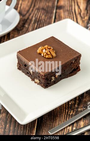 Brownie de noyer et de chocolat noir sur une assiette en porcelaine blanche sur une table en bois Banque D'Images