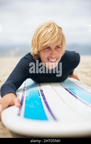 Juste un court passage avant de se diriger dans l'eau. Coupe courte d'une surfeuse couchée sur sa planche de surf. Banque D'Images