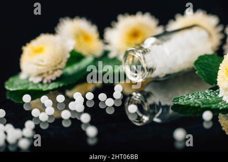 Globules homéopathiques dispersés dans une bouteille en verre Banque D'Images