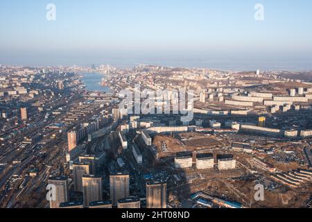 Vladivostok, Russie - 5 février 2022 : Vue d'en haut des maisons et des rues de la ville. À l'horizon, vous pouvez voir la mer et les ponts. Banque D'Images