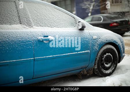 La voiture a gelé dans le parking. Vue latérale de transport. La voiture est couverte de glace. Couche de neige sur la voiture. Banque D'Images