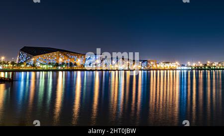 Vue en soirée sur une ville à côté de la plage avec des reflets lumineux et colorés sur l'eau Banque D'Images