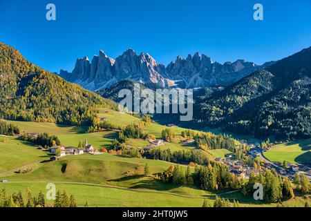 Vue aérienne de l'église et du village de Saint-Magdalena dans la vallée de Villnöss, faces nord et sommets du groupe Odle au loin, en automne. Banque D'Images
