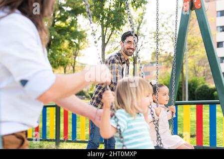 Couple gay regardant les uns les autres jouer avec leurs enfants Banque D'Images