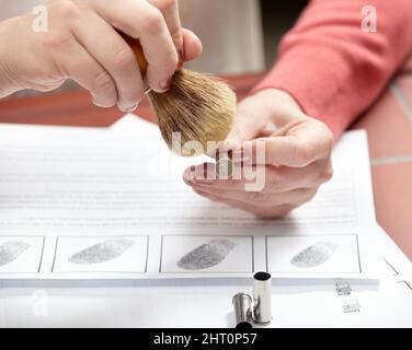 Examen détaillé pour attraper le criminel. Photo rognée d'un scientifique en médecine légale dépoussiérant une balle au-dessus d'une impression sans traces de doigts. Banque D'Images