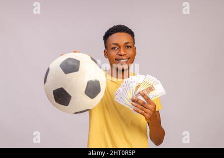 Sport misez excitation, joueur et style de vie de famille concept. Un jeune gars afro-américain enthousiaste qui apprécie leur victoire, se tenant avec le ballon de football et beaucoup Banque D'Images