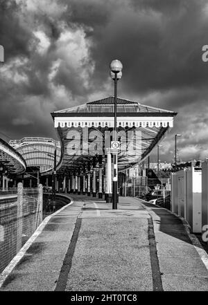 Un chemin en pente mène à une voûte historique de la gare avec une voûte voûtée en arrière-plan. Un ciel avec des nuages sombres est au-dessus. Banque D'Images