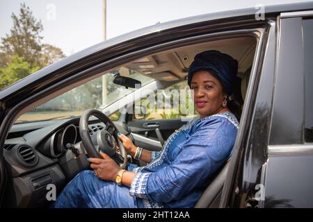 Femme africaine assise à l'intérieur de la voiture avec ses mains saisissant le volant Banque D'Images