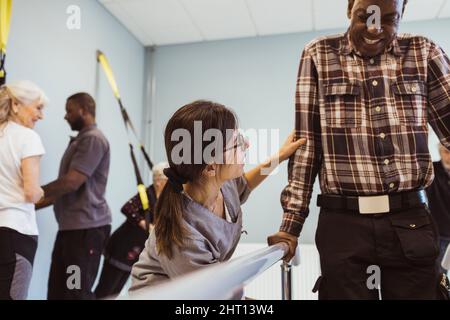 Une travailleuse de la santé aide l'homme âgé à marcher à la maison de retraite Banque D'Images