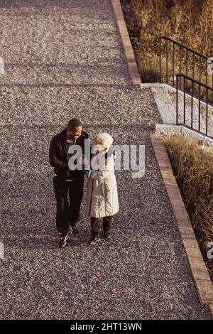 Vue en grand angle d'une infirmière qui marche avec une femme âgée dans le parc Banque D'Images